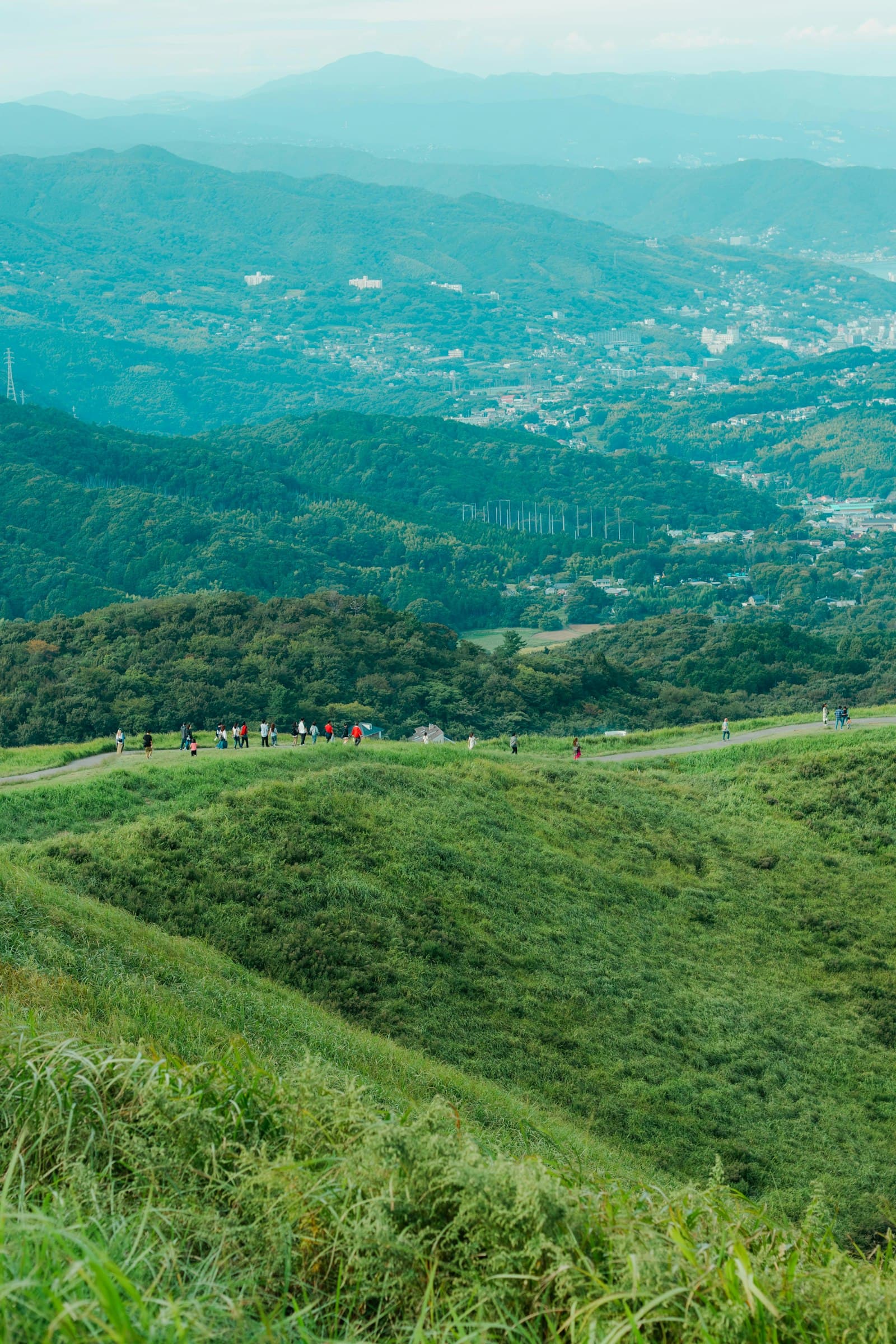 Walkers along a hilltop trail above a Japanese valley